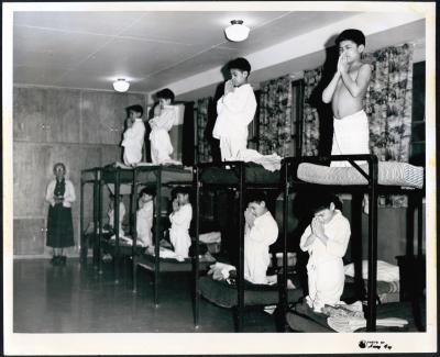 Photograph of boys praying on bunk beds in dormitory