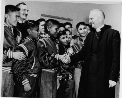 Photograph of Black Hawks boy's hockey team being congratulated by Bishop Jefferson