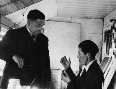 Photograph of two men speaking in a woodworking shop
