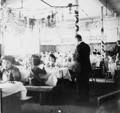 Photograph of Rev. G.A. Crawley reading to students eating Christmas dinner