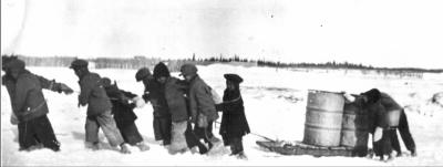 Photograph of a group of boys pulling a sled across the snow